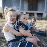 Baby in denim romper cuddled with sister