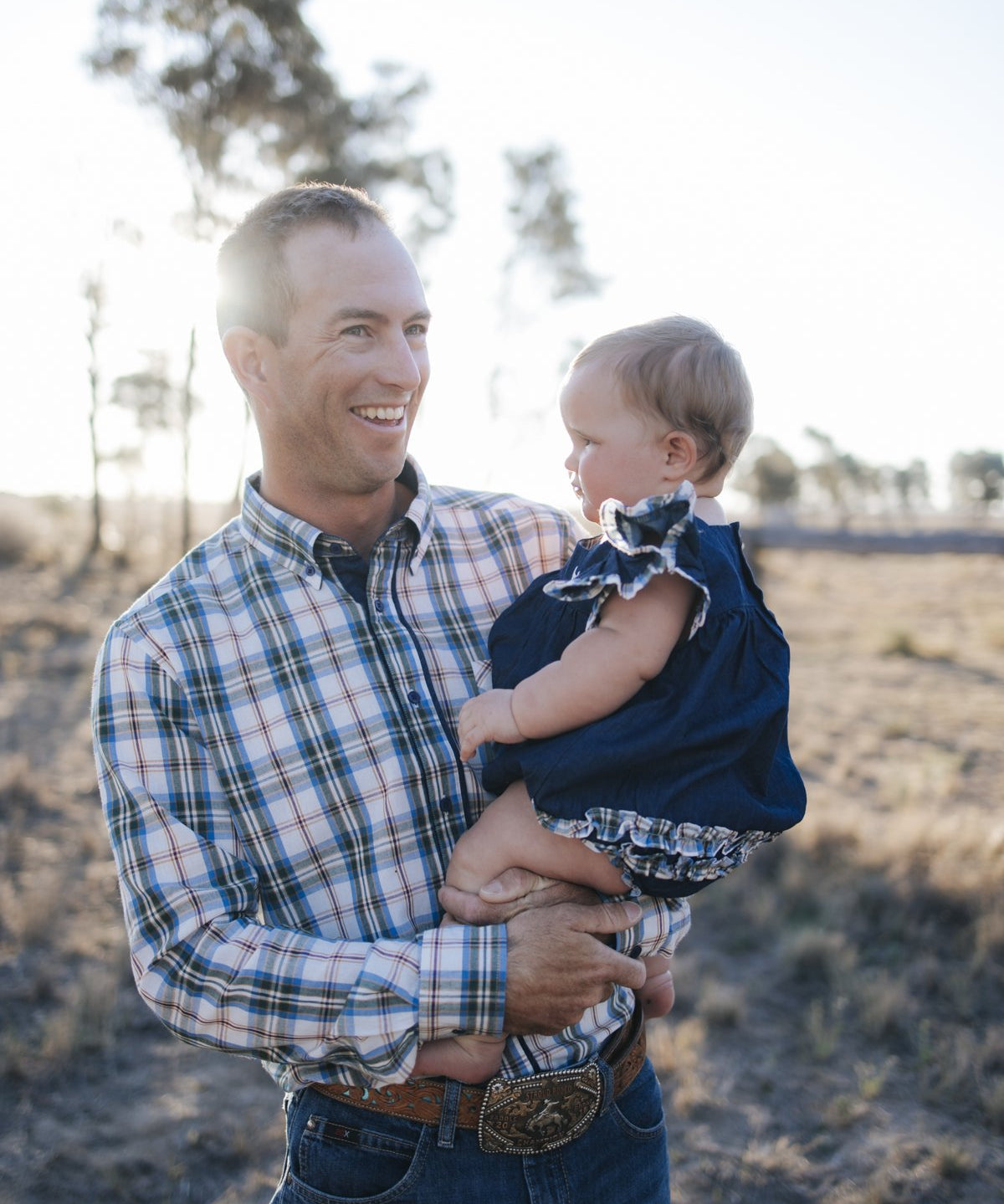 Man in blue plaid shirt holding baby