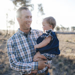 Man in blue plaid shirt holding baby