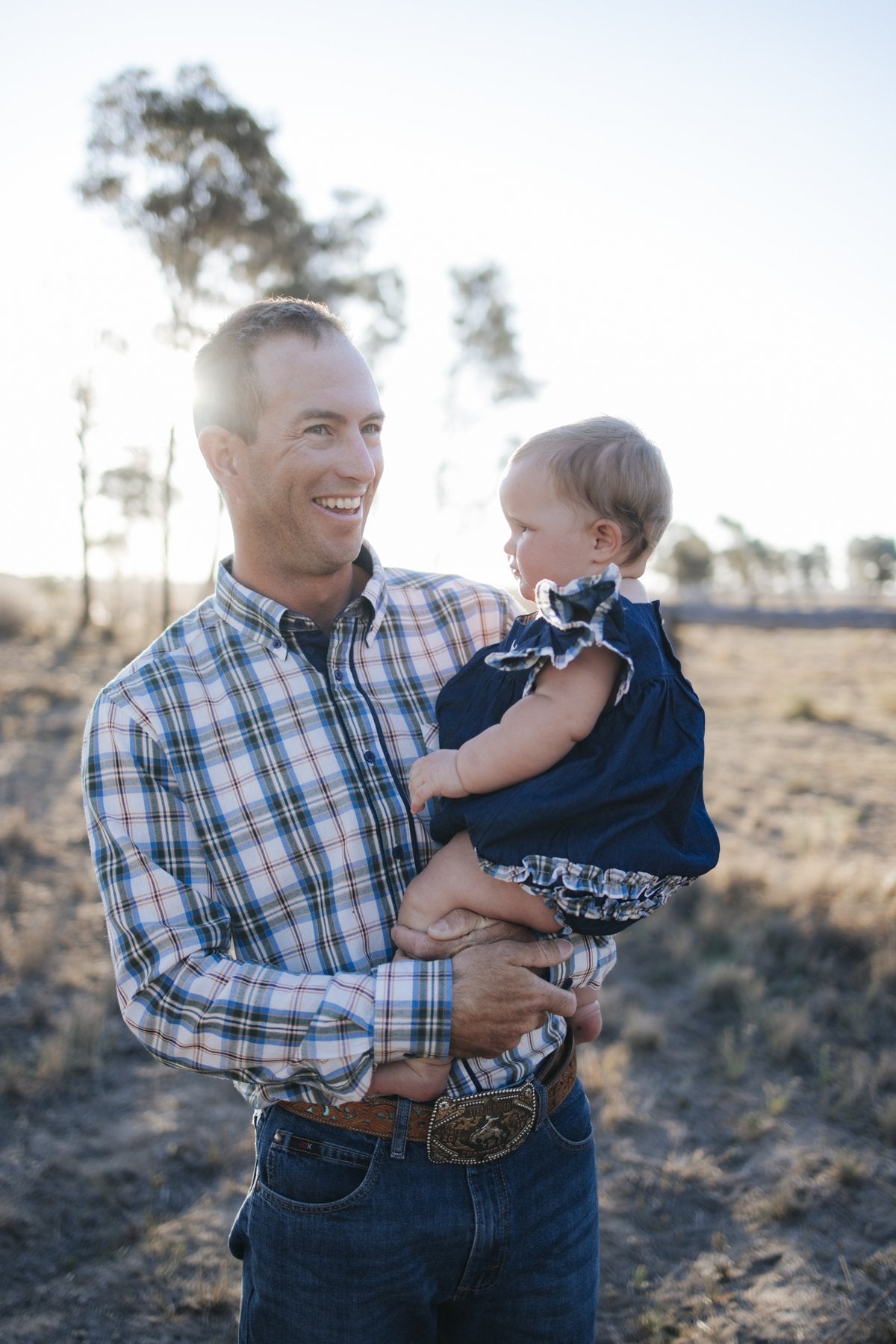 Man in blue plaid shirt holding baby