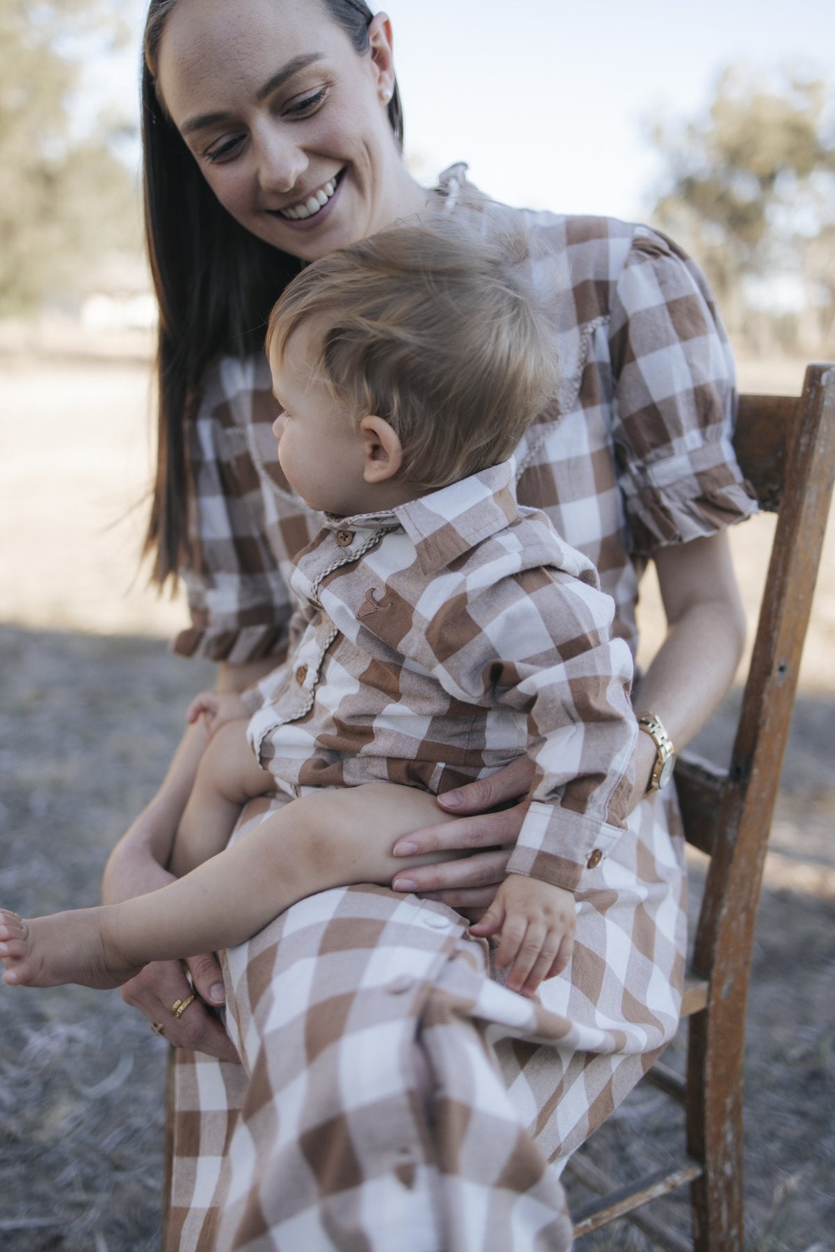 Baby boy gingham bodysuit on mum's lap