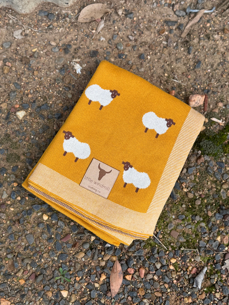 Yellow blanket with sheep pattern on a textured surface