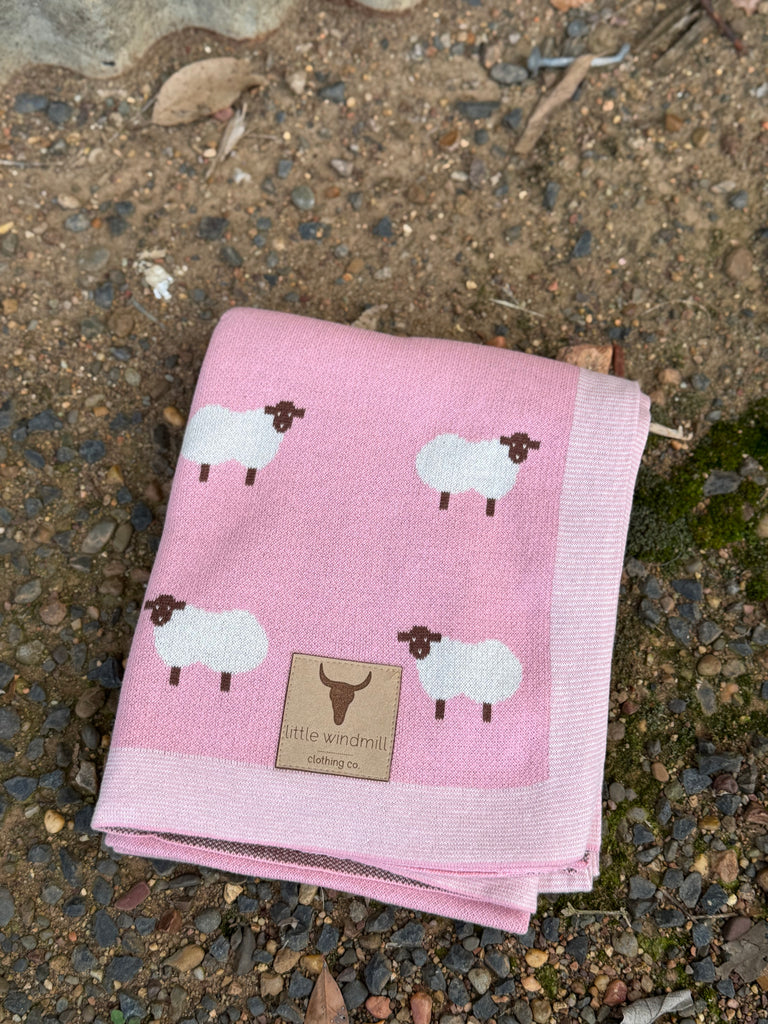 Pink blanket with sheep pattern on a stone surface