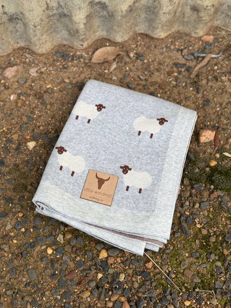 Grey blanket with sheep pattern on a textured surface