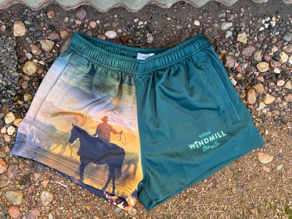 Two pairs of shorts on a gravel surface, one green with 'Wrendale' branding, the other with a nature-themed design.