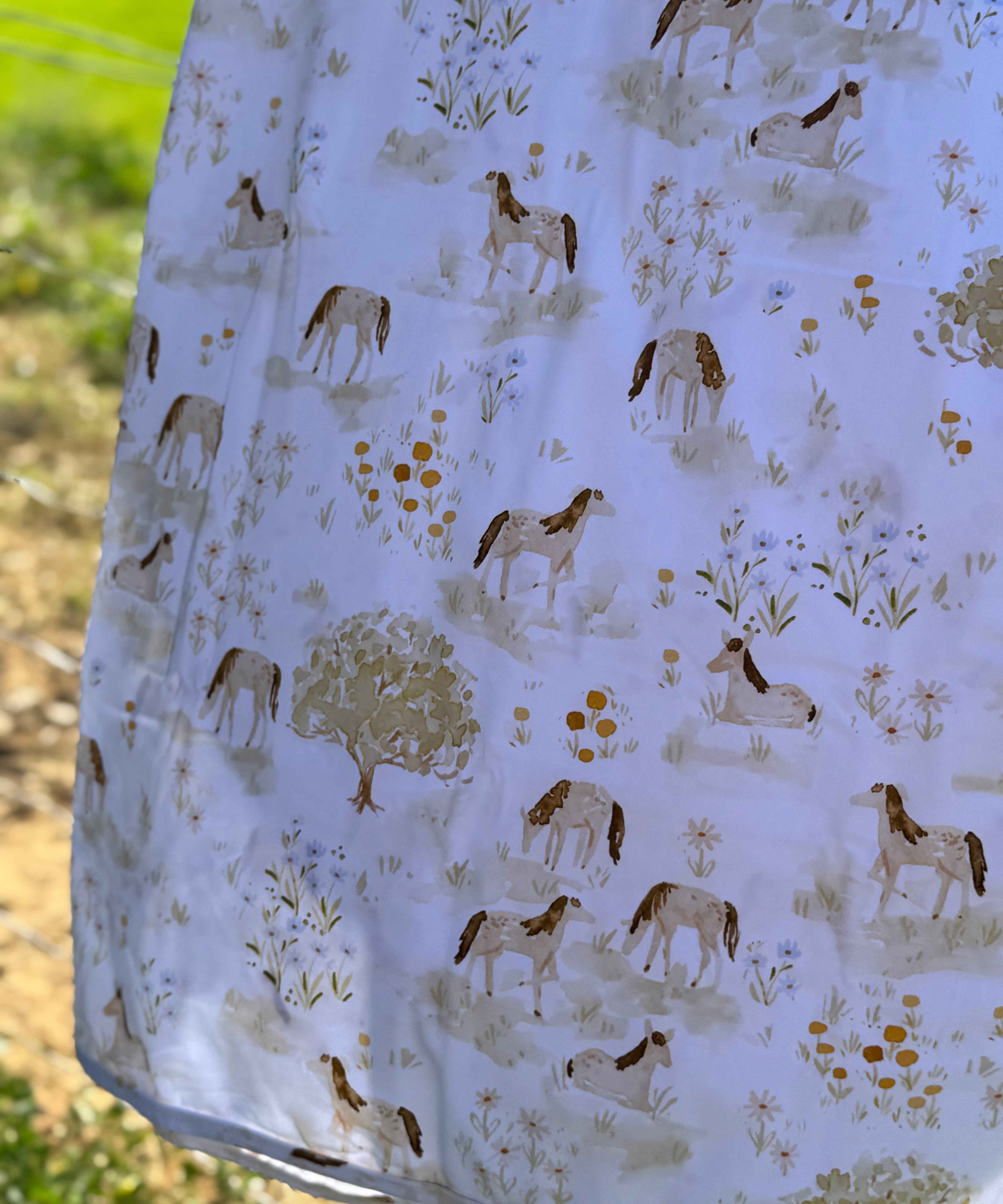 Horse field swaddle print close-up showing detailed horse field scene on soft organic jersey cotton
