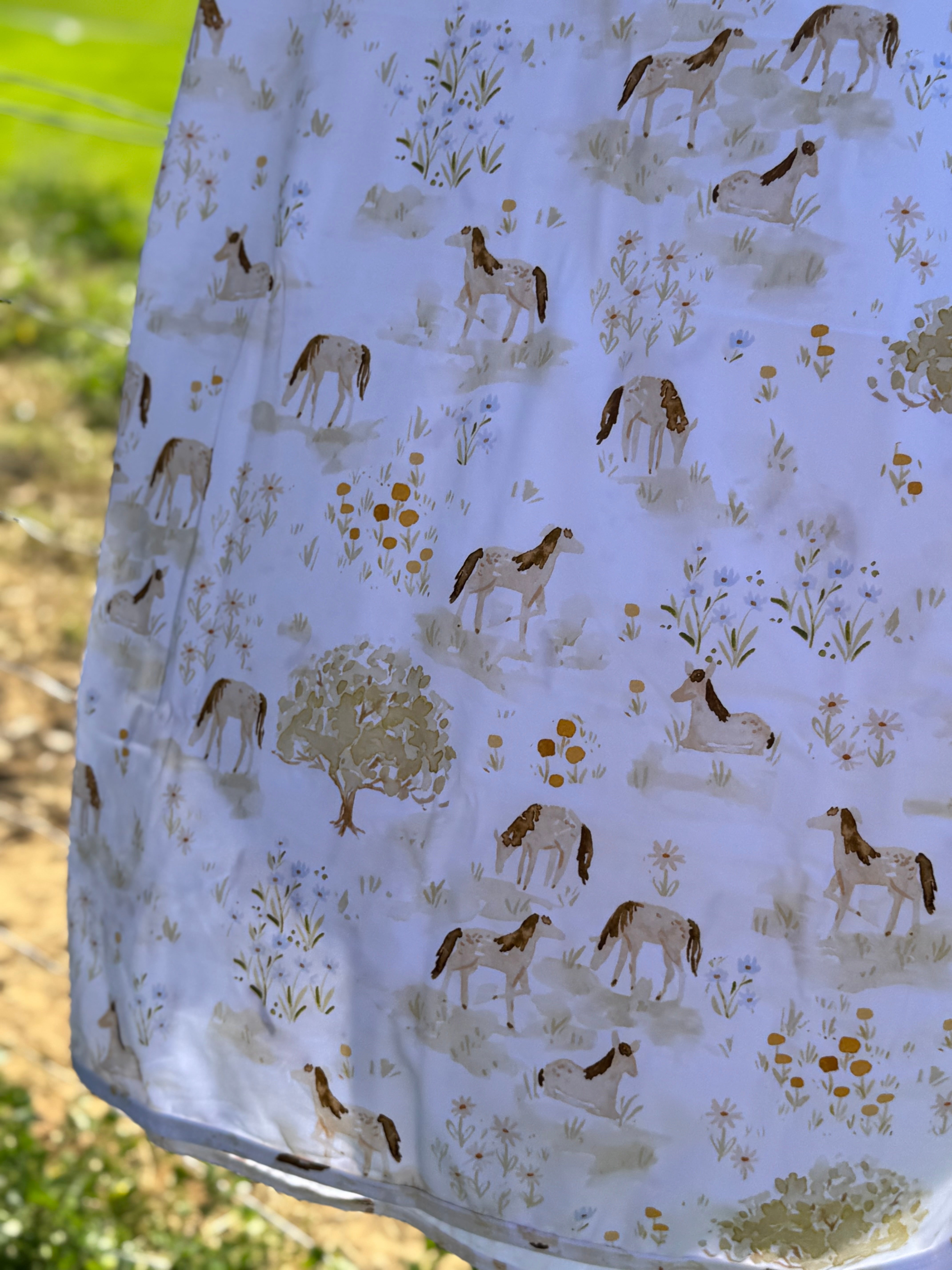 Horse field swaddle print close-up showing detailed horse field scene on soft organic jersey cotton