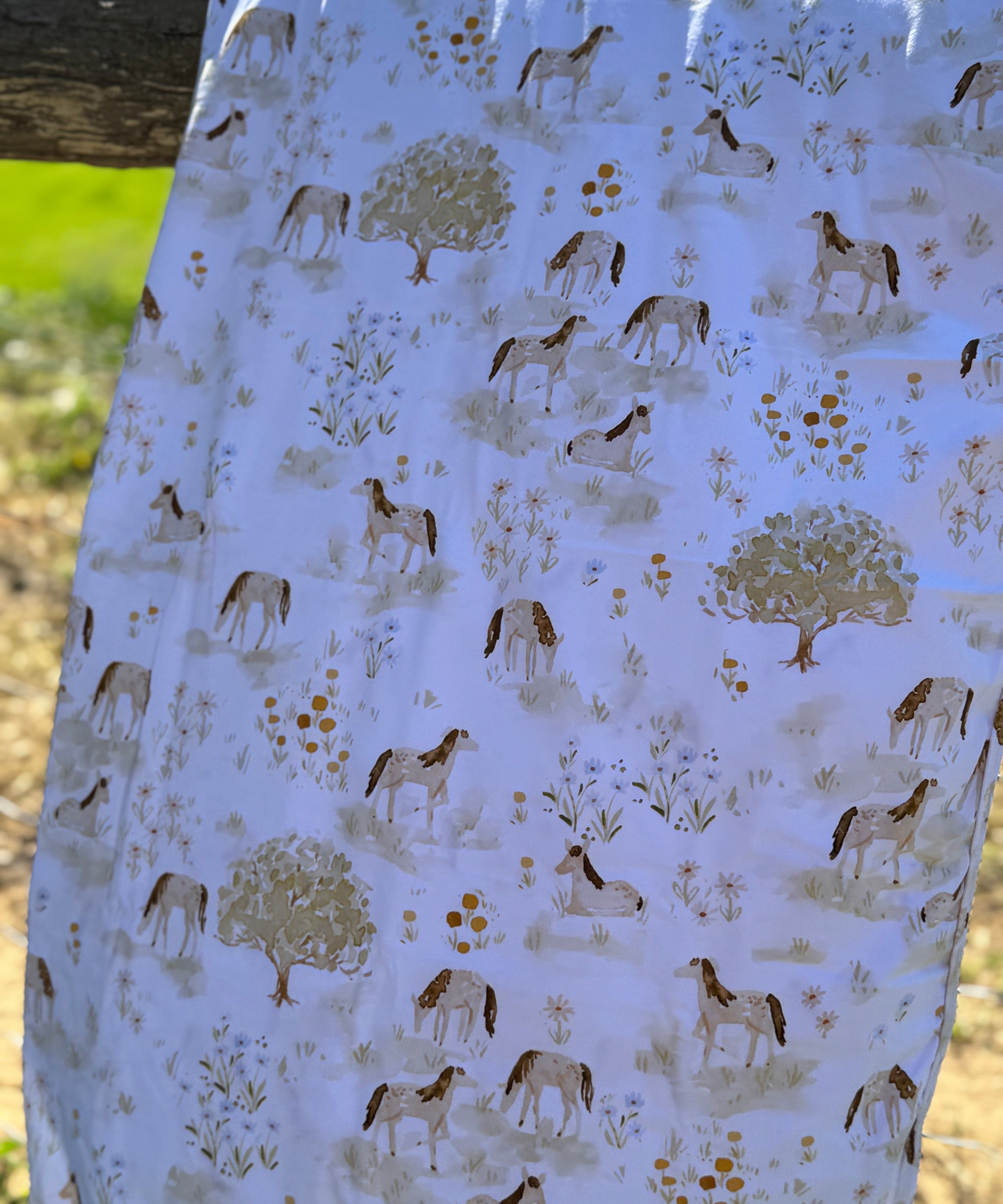 Horse field organic cotton swaddle draped showing generous size for swaddling and wrapping