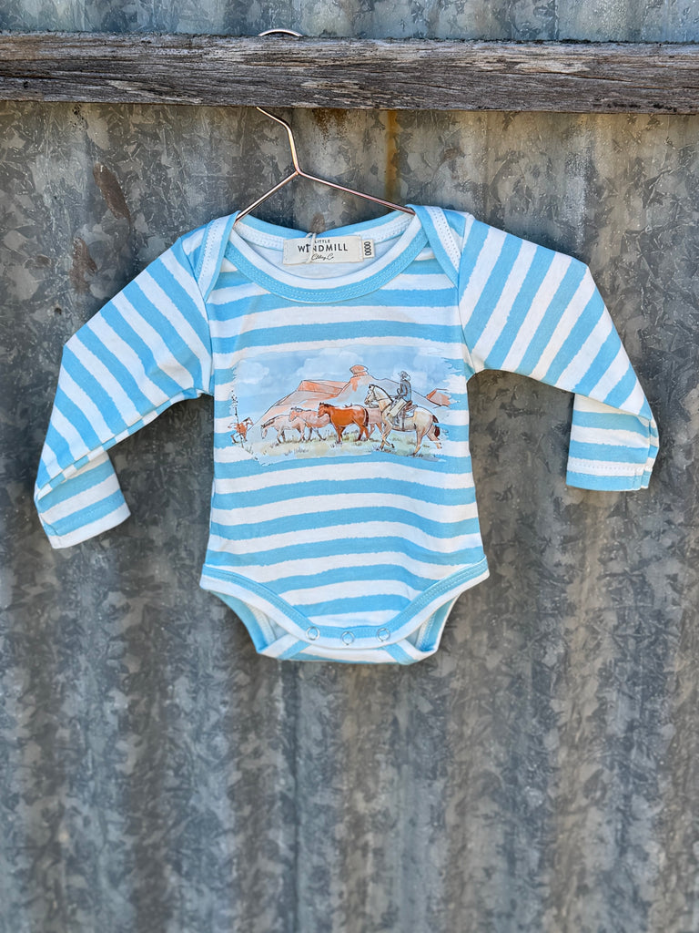 Blue and white striped baby onesie with animal design on a hanger against a rustic metal wall.