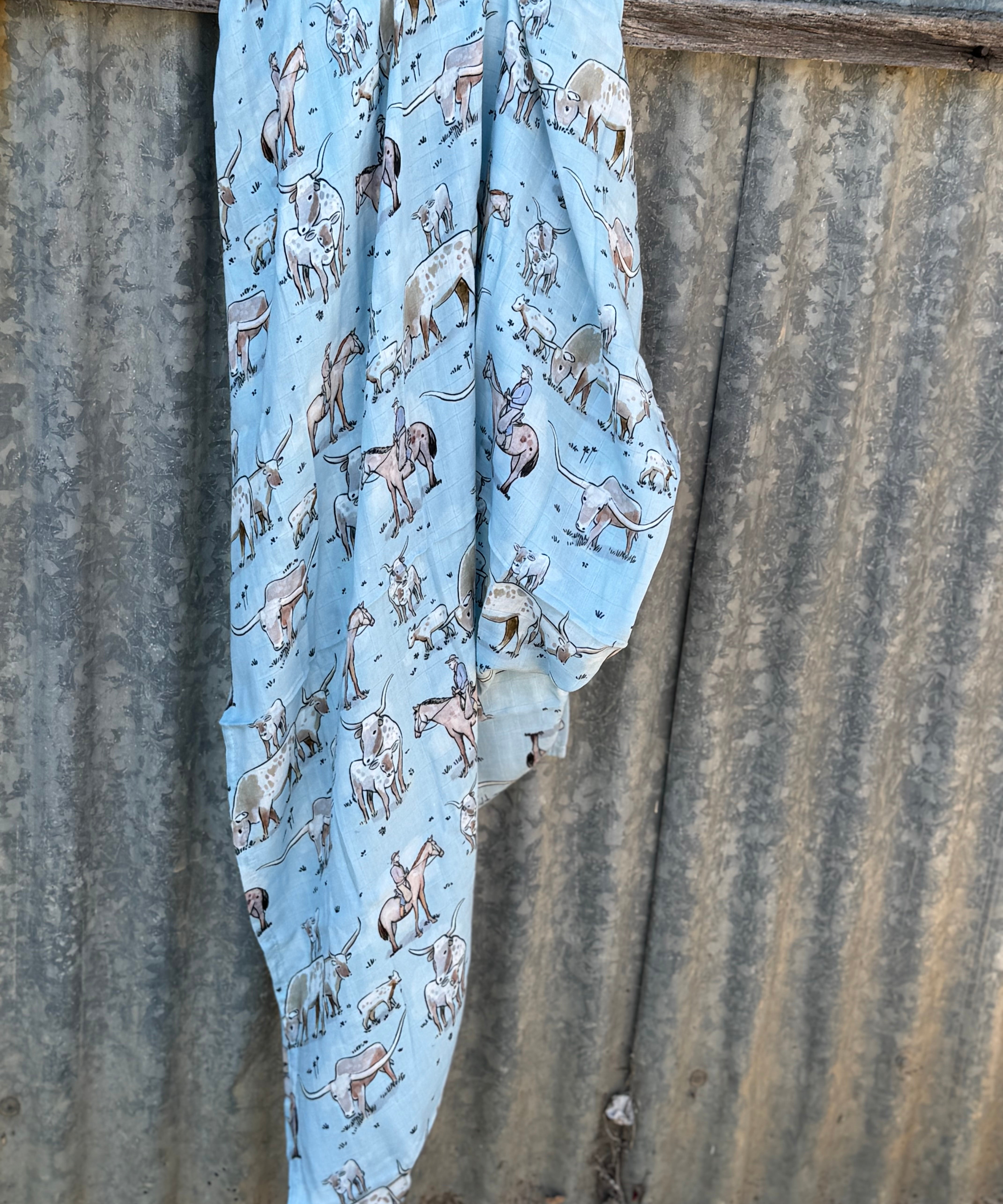 Blue longhorn organic muslin swaddle draped showing lightweight breathable swaddle for warmer weather