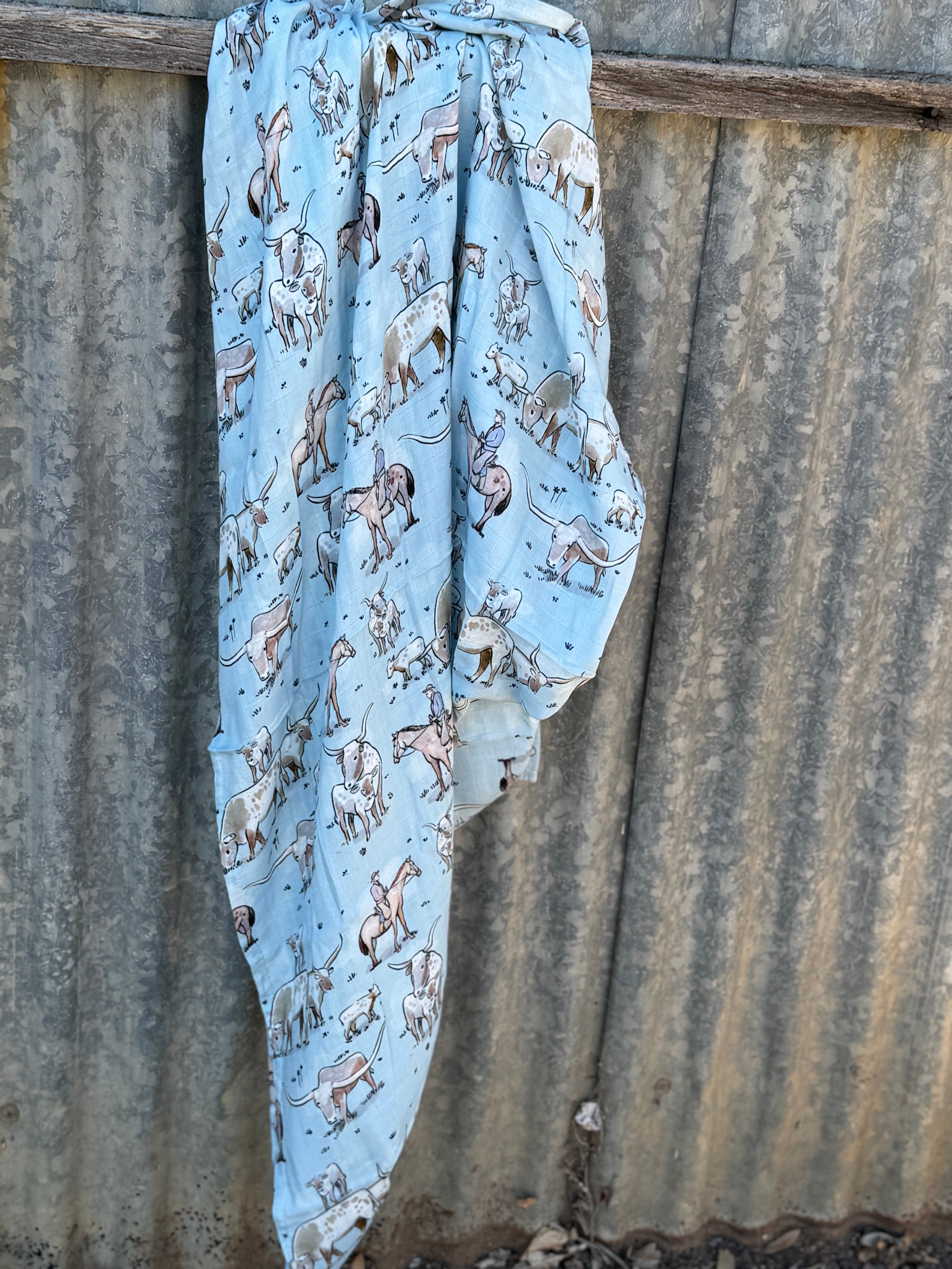 Blue longhorn organic muslin swaddle draped showing lightweight breathable swaddle for warmer weather