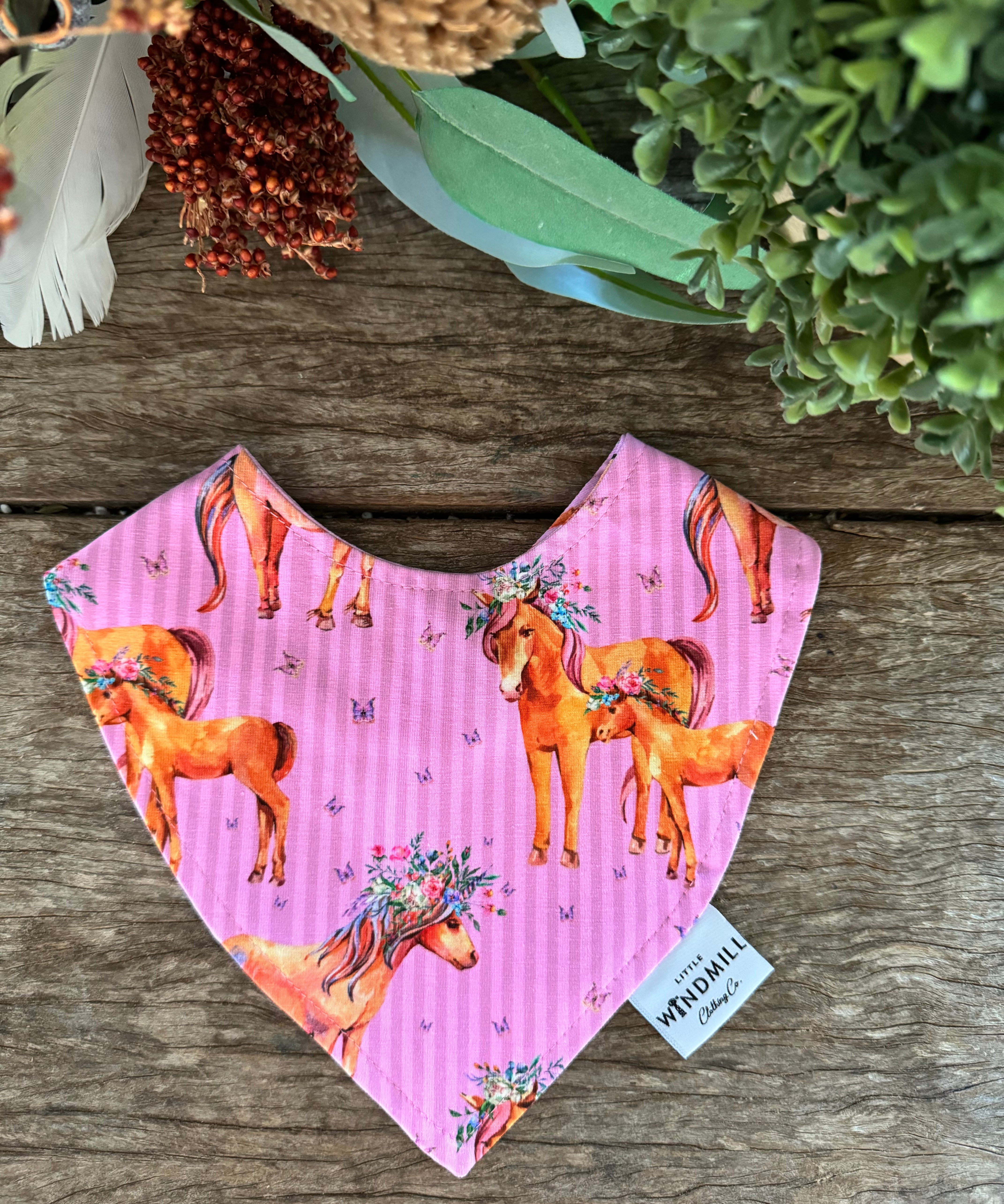 Waterproof pink horses bib showing adorable horse print design on wipeable waterproof fabric
