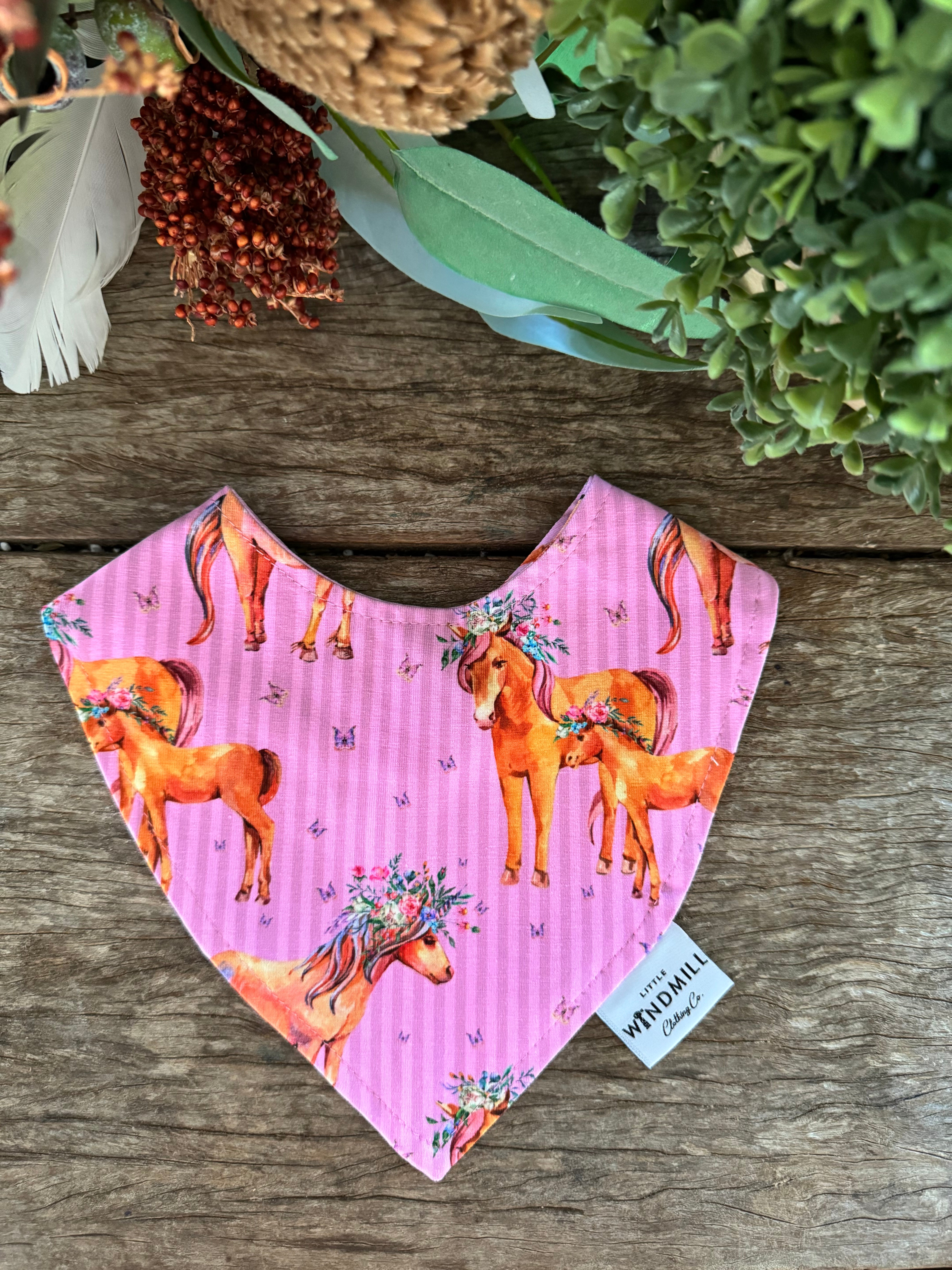 Waterproof pink horses bib showing adorable horse print design on wipeable waterproof fabric