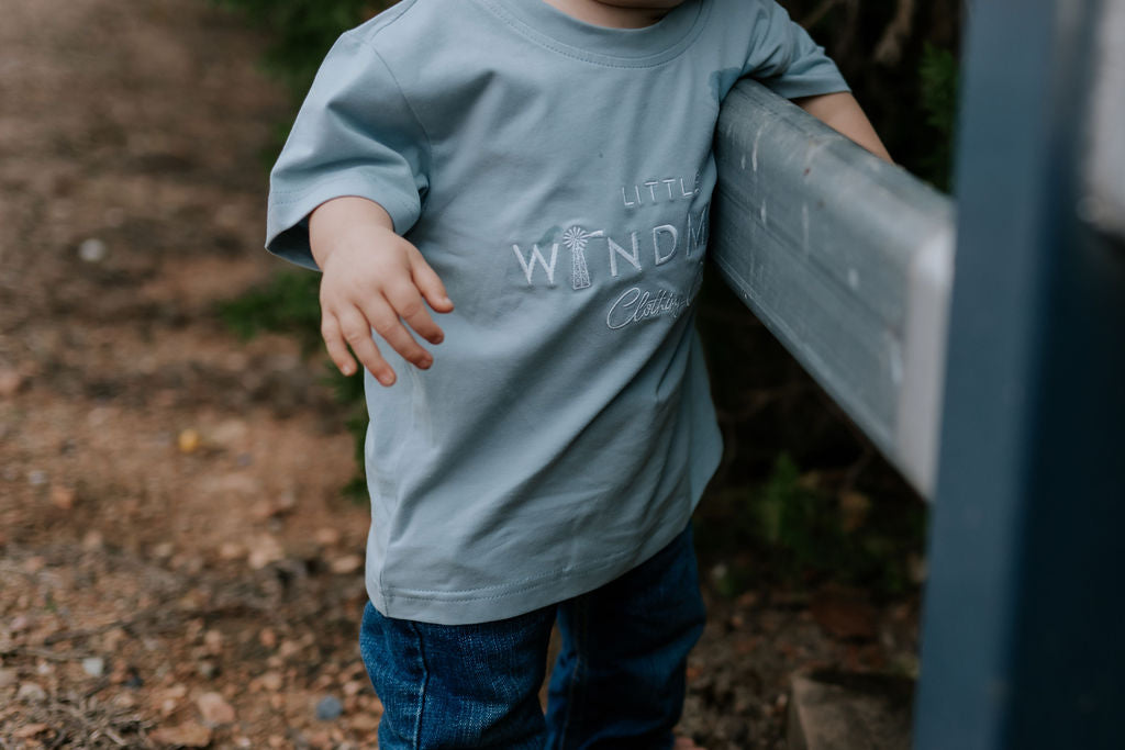 LWCC embroidered kids tee powder blue flatlay showing full design and soft powder blue colourway