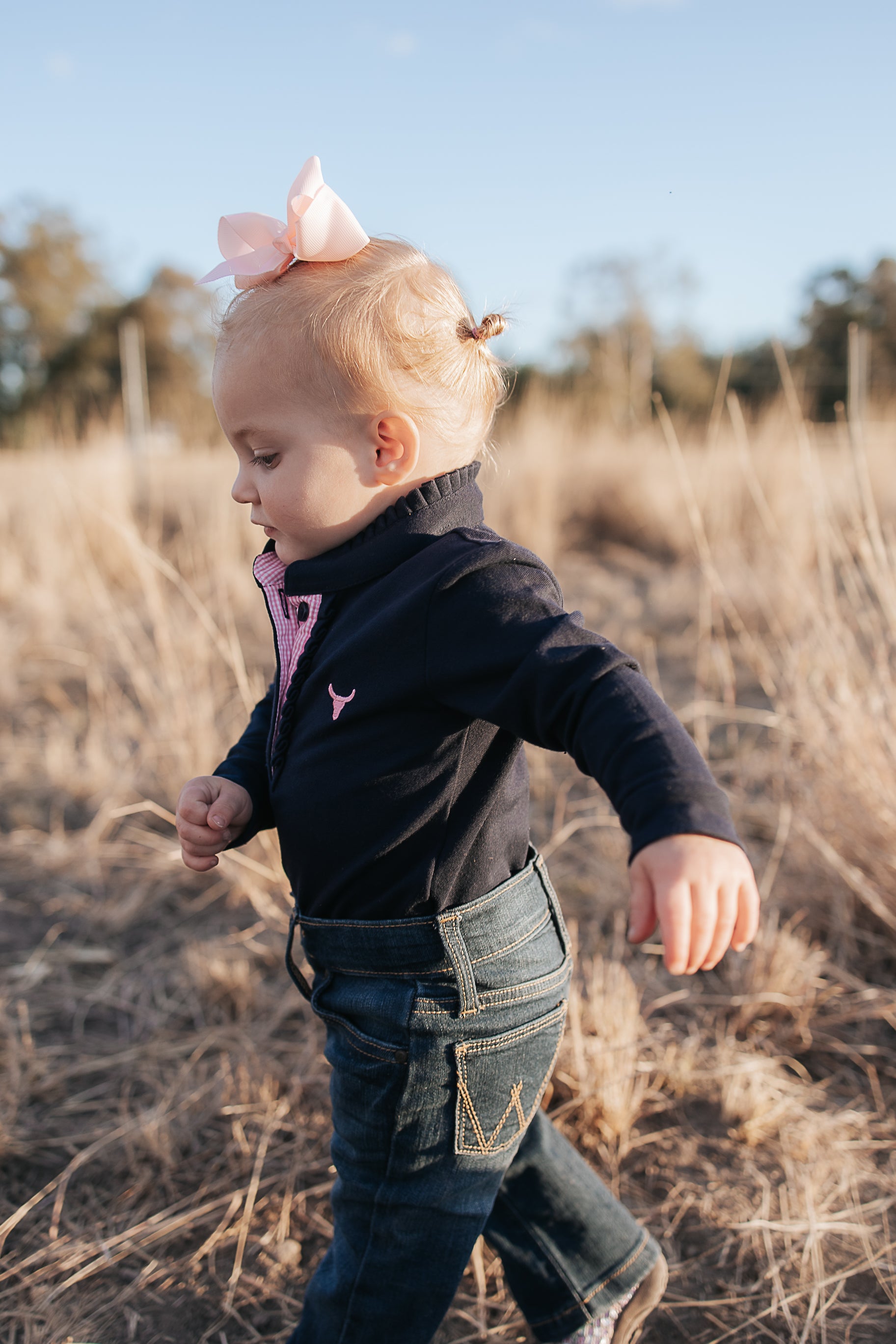 BB Baby navy ruffle pink gingham contrast long sleeve baby polo romper back view showing snap closure and baby fit