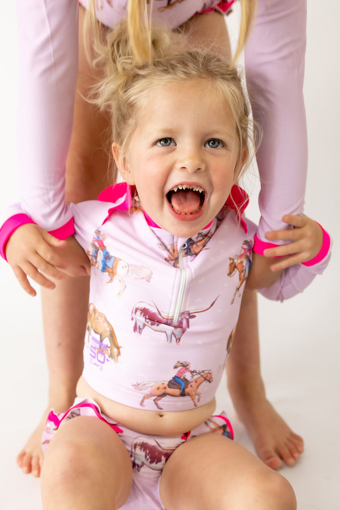 Child wearing a pink animal-themed swimsuit with a white background