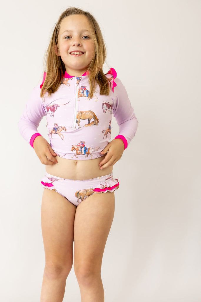 Child wearing a pink and white swimsuit with animal prints on a plain background