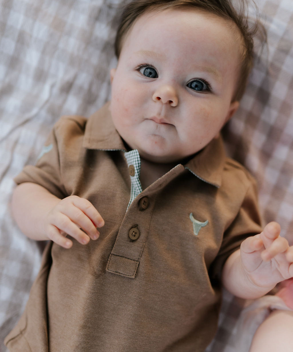 Clay Baby caramel baby polo romper front view showing warm caramel polo collar romper with snap buttons