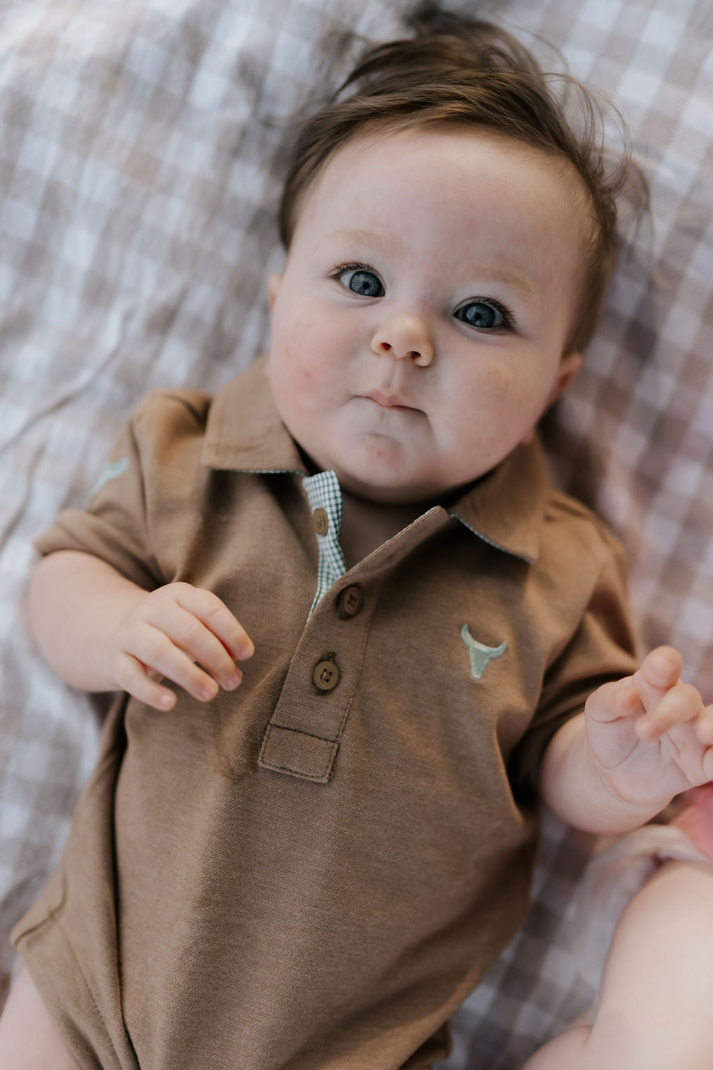 Clay Baby caramel baby polo romper front view showing warm caramel polo collar romper with snap buttons