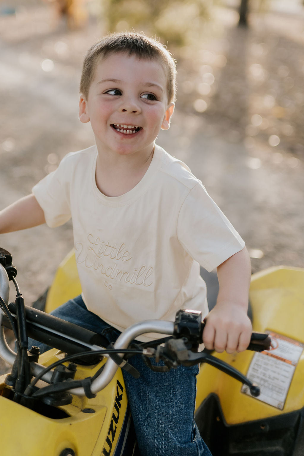 LIMITED EDITION embroidered kids tee cream embroidery close-up showing detailed LWCC logo on cream fabric
