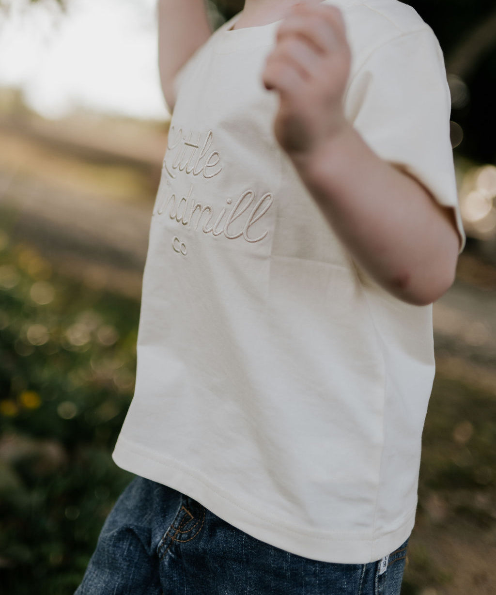LIMITED EDITION embroidered kids tee cream front view showing signature LWCC embroidered logo on classic cream