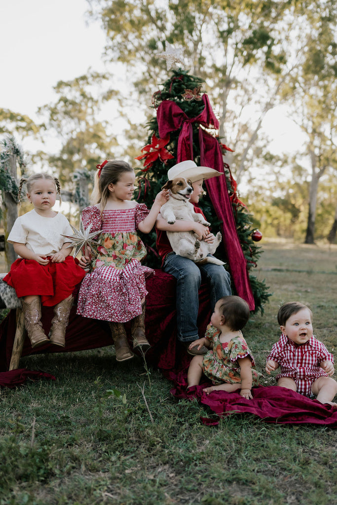 Children and a dog sitting on a decorated Christmas tree in an outdoor setting.