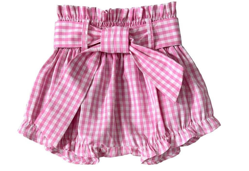 Pink gingham check baby bloomers with a bow on a gray background