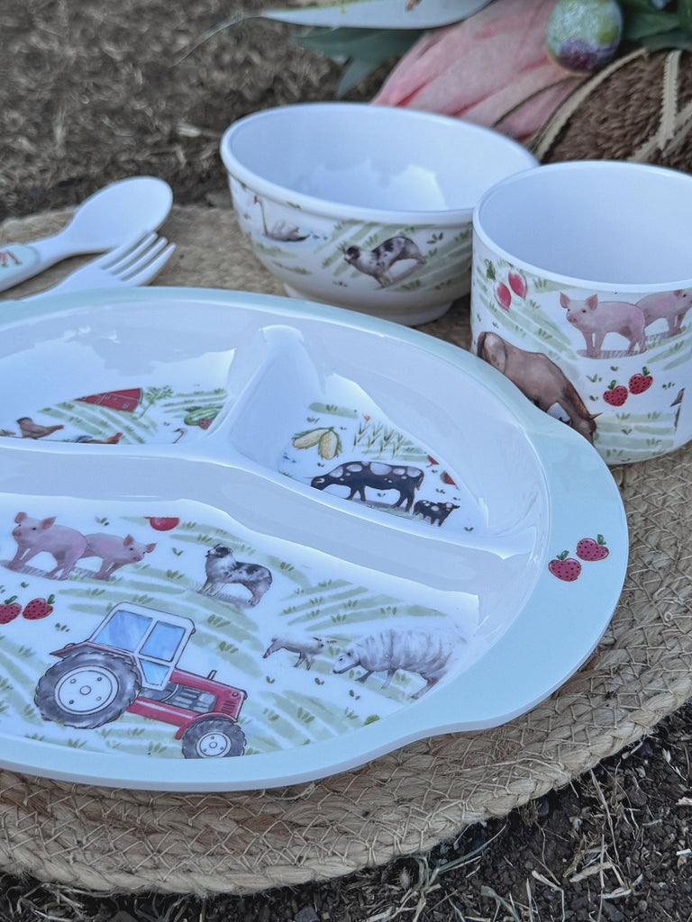 Children's dinner set with plate, bowl, and cup featuring farm animal designs on a textured surface.