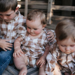 Siblings in matching brown check shirt and rompers