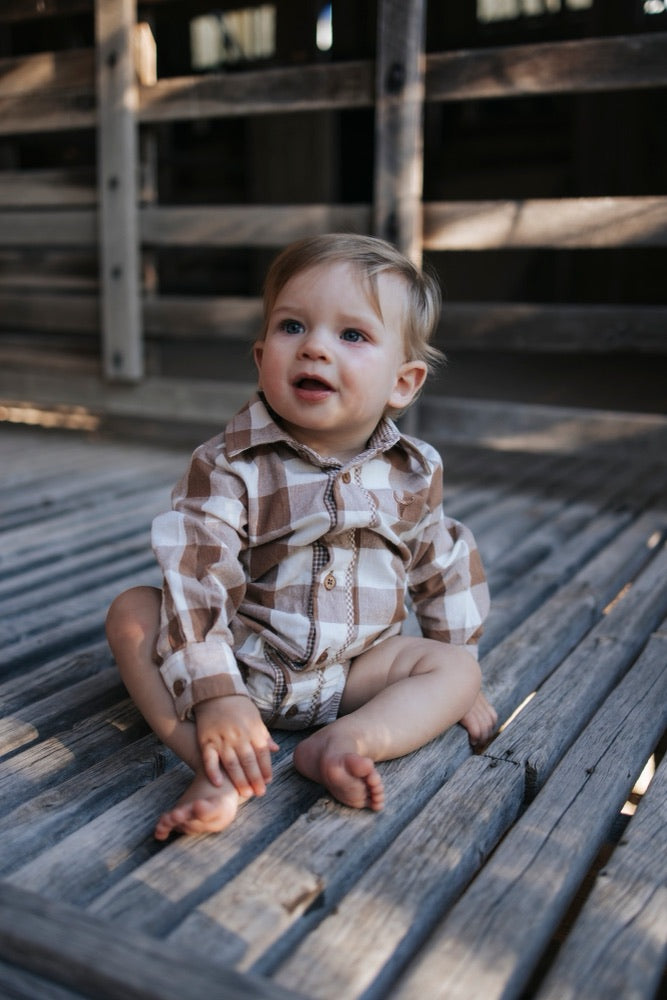 Baby boy in a brown check long-sleeve romper