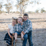 Three siblings in blue plaid shirts and a navy denim tiered skirt