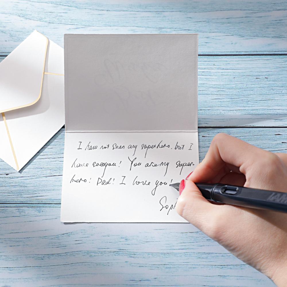 Handwriting a personal gift message on a card with an envelope on wooden surface