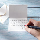 Handwriting a personal gift message on a card with an envelope on wooden surface
